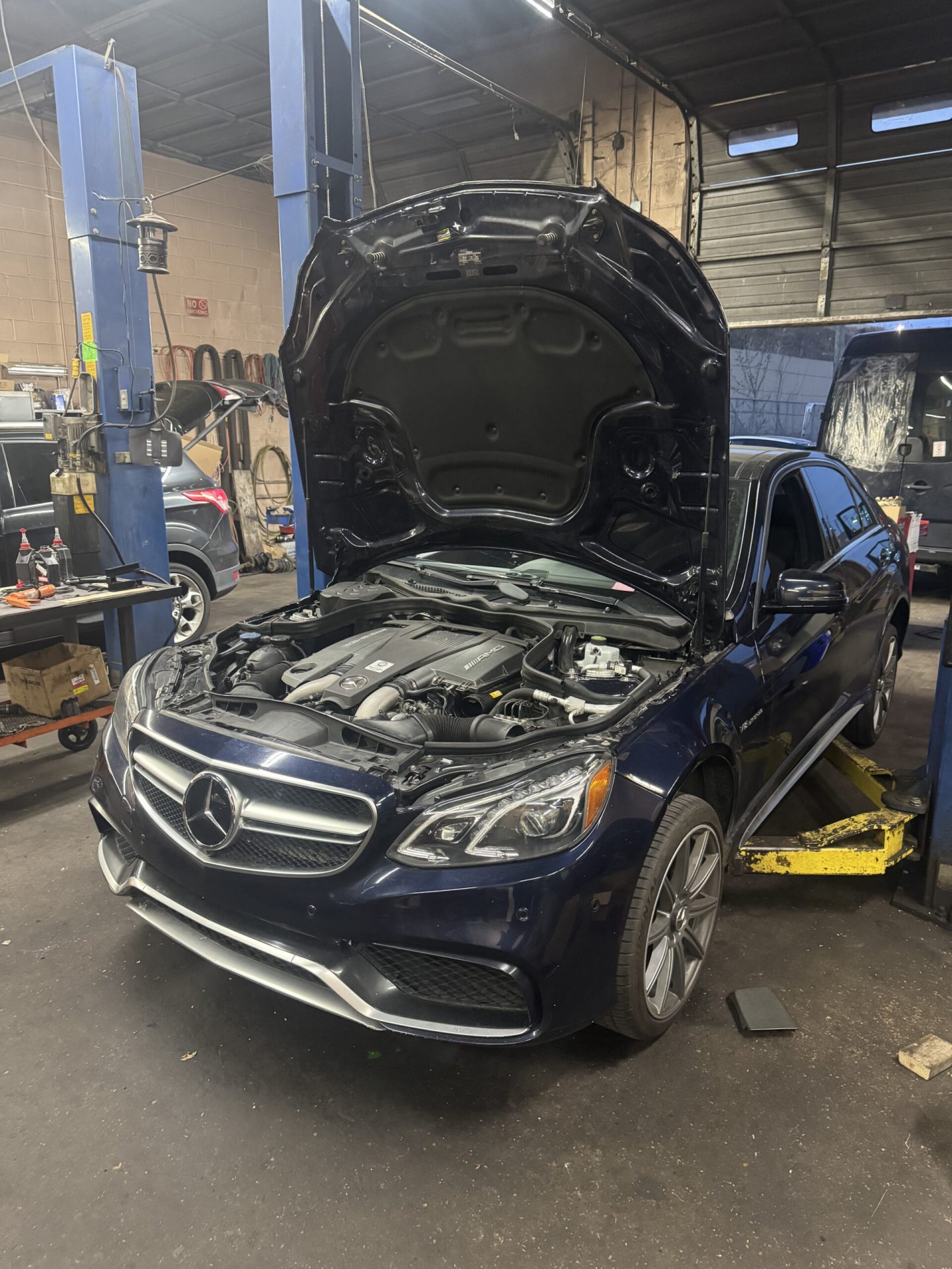 Dark blue Mercedes-Benz E63 AMG W212 with hood open for engine service at TOP CONCEPT auto repair shop in Philadelphia