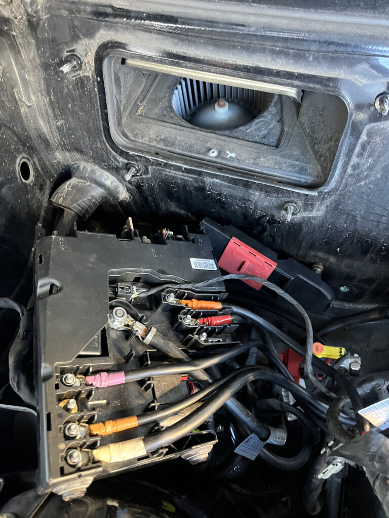 Close-up of Mercedes-Benz C-Class fuse box and battery distribution block with red power cable and fuse links during electrical repair