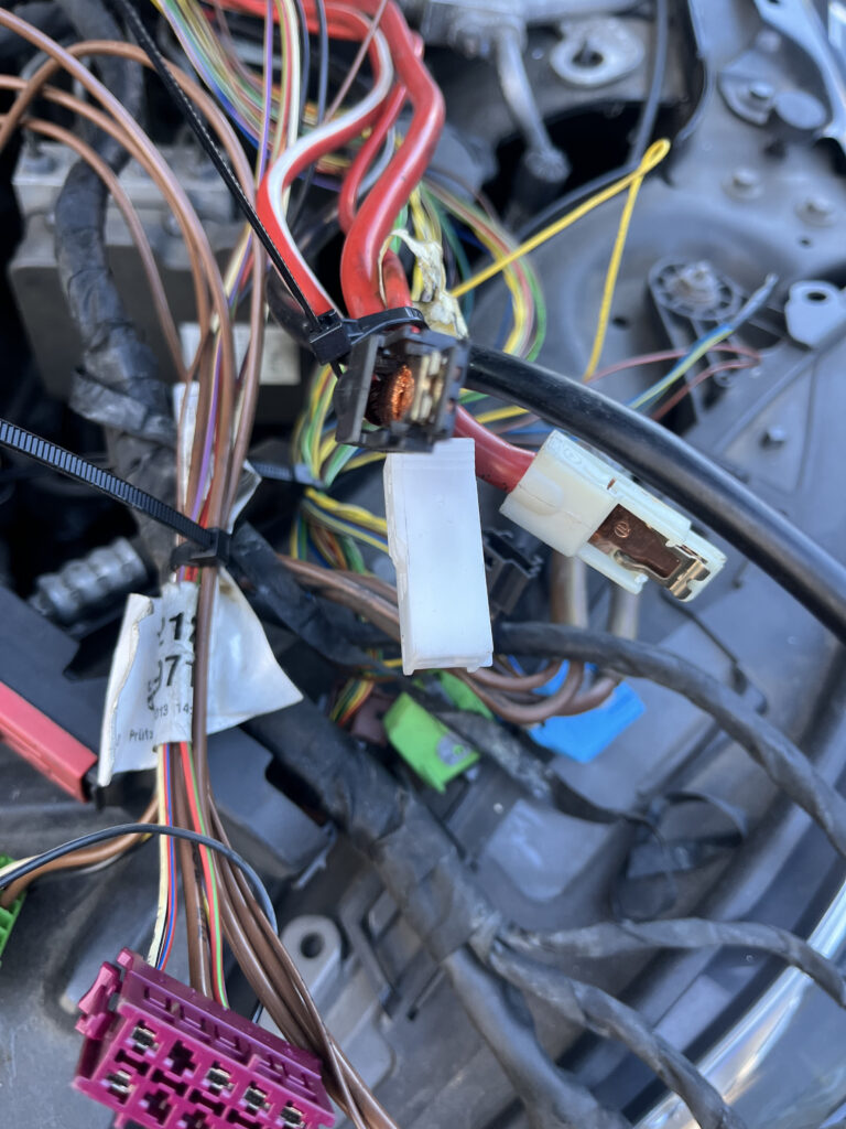 Detail view of Mercedes-Benz wiring harness connectors including pink fuel injector plug and white sensor connector during diagnosis